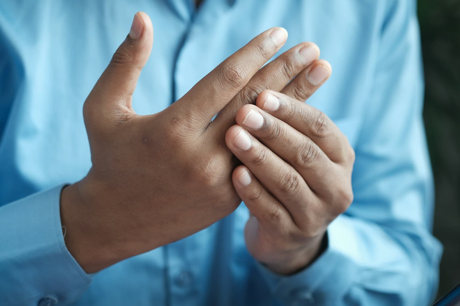 Persona in camicia azzurra che mostra il palmo della mano sinistra